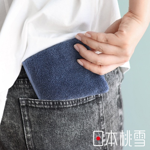 圖片中的文字為「日本桃雪」。此圖為視覺描述模式，圖片顯示一名女子將一塊深藍色的毛巾放入口袋。