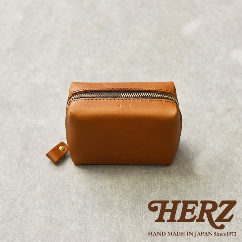 職人手作皮革Organ箱型收納包，駝色皮革，拉鍊開合，附有品牌標誌。