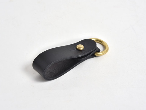 黑色皮革吊掛扣帶，搭配黃銅色金屬環和鉚釘。