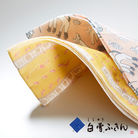 兩條友禪染廚房長拭巾，一條為粉橘色背景印有灰色貓咪圖案，另一條為黃色背景印有粉色小魚和邊框裝飾圖案，材質為棉質，觸感柔軟。