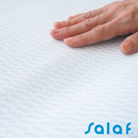 手輕觸白色細緻紋理的涼感枕套，左下方印有藍色「Salaf」品牌標誌。