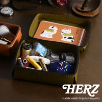 橄欖綠皮革收納盒內有針線、鈕扣、剪刀等縫紉工具，以及兩張招財貓圖案的卡片。旁邊另有一個棕色皮革小物收納盒。