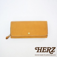 職人手作皮革長夾，焦糖棕色，寬口設計，側邊有拉鍊，正面有一個金色金屬釦，車縫線為米白色。