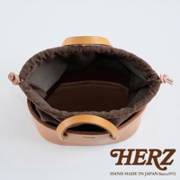 職人手作皮革束口手提包，天然皮革材質，可見圓形提把與束口設計，內裡為深棕色布料，整體呈現自然光澤。