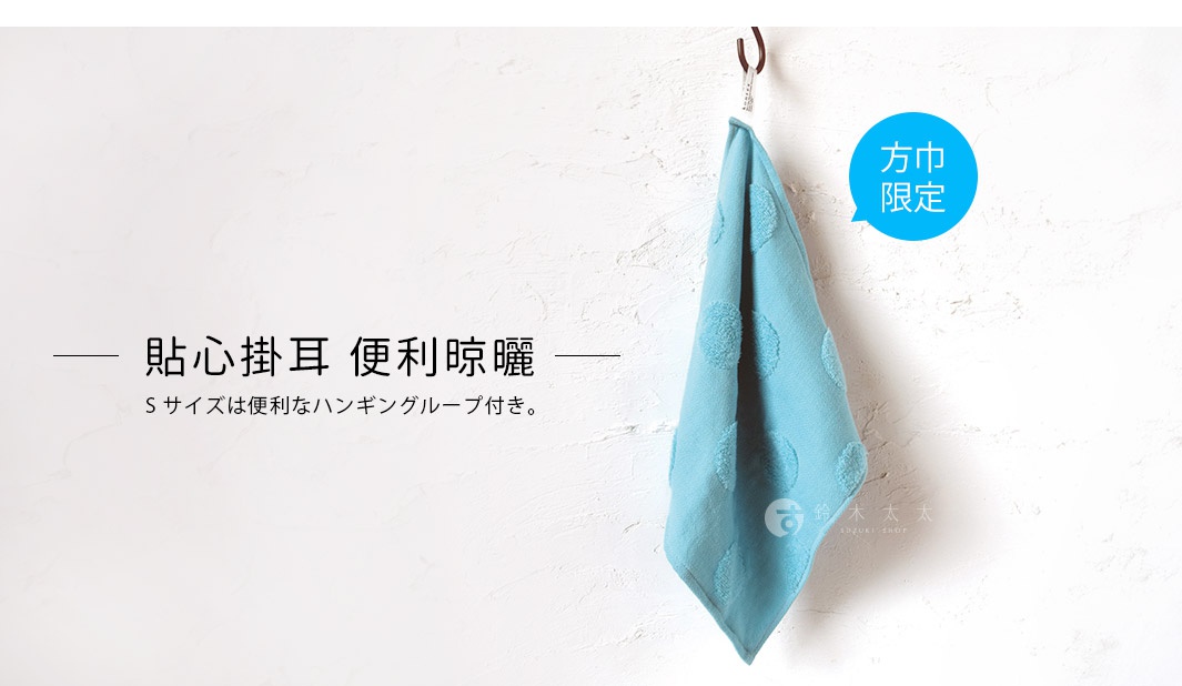 淺藍色無撚紗質毛巾，點綴立體水玉點點圖案，由掛鉤懸掛於白色牆面上。