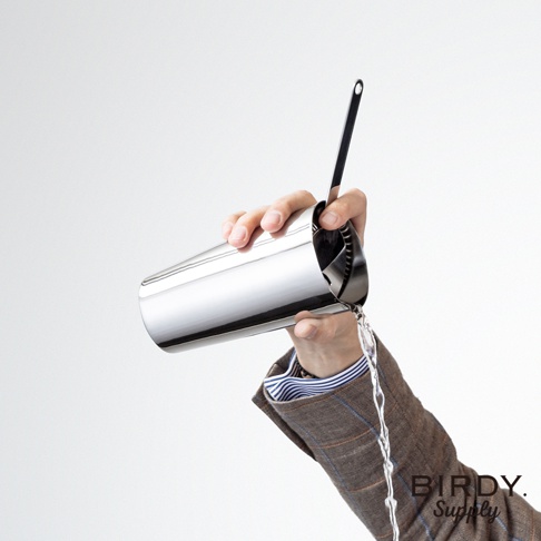 一只手拿著銀色不鏽鋼調酒杯，杯中有一根長柄濾酒隔冰匙，正在傾倒液體。