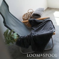 深灰色純棉立體直紋單人毯，質感微厚，柔軟舒適，搭配編織籃與簡約座椅，呈現溫馨居家氛圍。