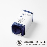 深藍色毛絨質地的專髮擦髮巾，包裝在透明塑膠盒內，盒上有日文說明與人像圖示，下方有「OBORO TOWEL」品牌標誌。