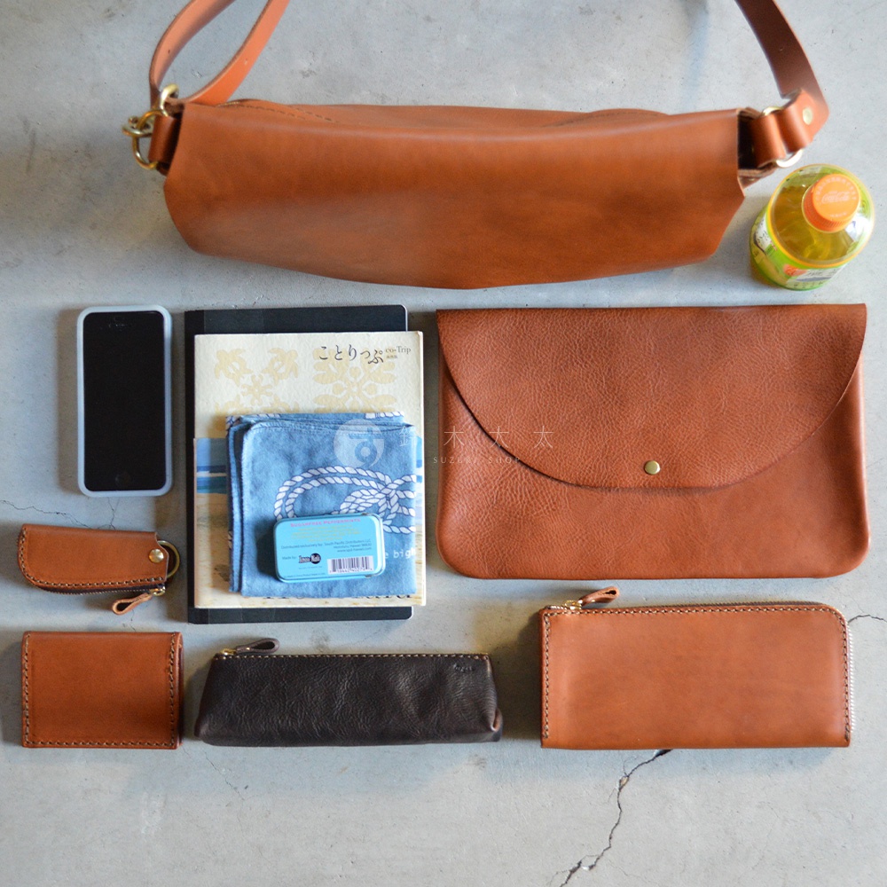 職人手作皮革Organ隨身斜背包，搭配手機、筆記本、手帕、薄荷糖、鑰匙包、零錢包、長夾和一個封蓋式皮革包。