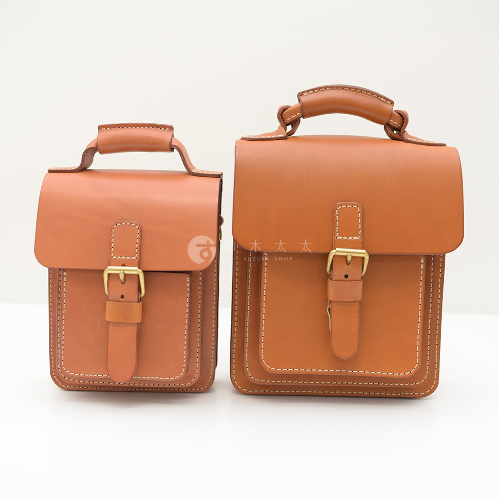 兩款棕褐色皮革單肩兩用小方包，皆為方正包型，配有頂部提把、翻蓋式開口、銅色金屬扣環及皮帶束口，包身有明顯的車縫線細節，展現職人手作質感。