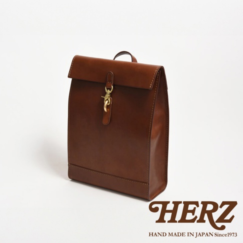 棕色皮革紙袋風後背包，具有金屬鉤扣和翻蓋設計，展現職人手作質感。