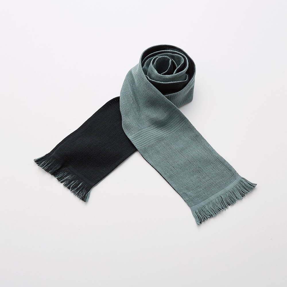 一條今治匹馬棉雙色圍巾，一端為黑色，另一端為灰綠色，兩端均帶有流蘇。