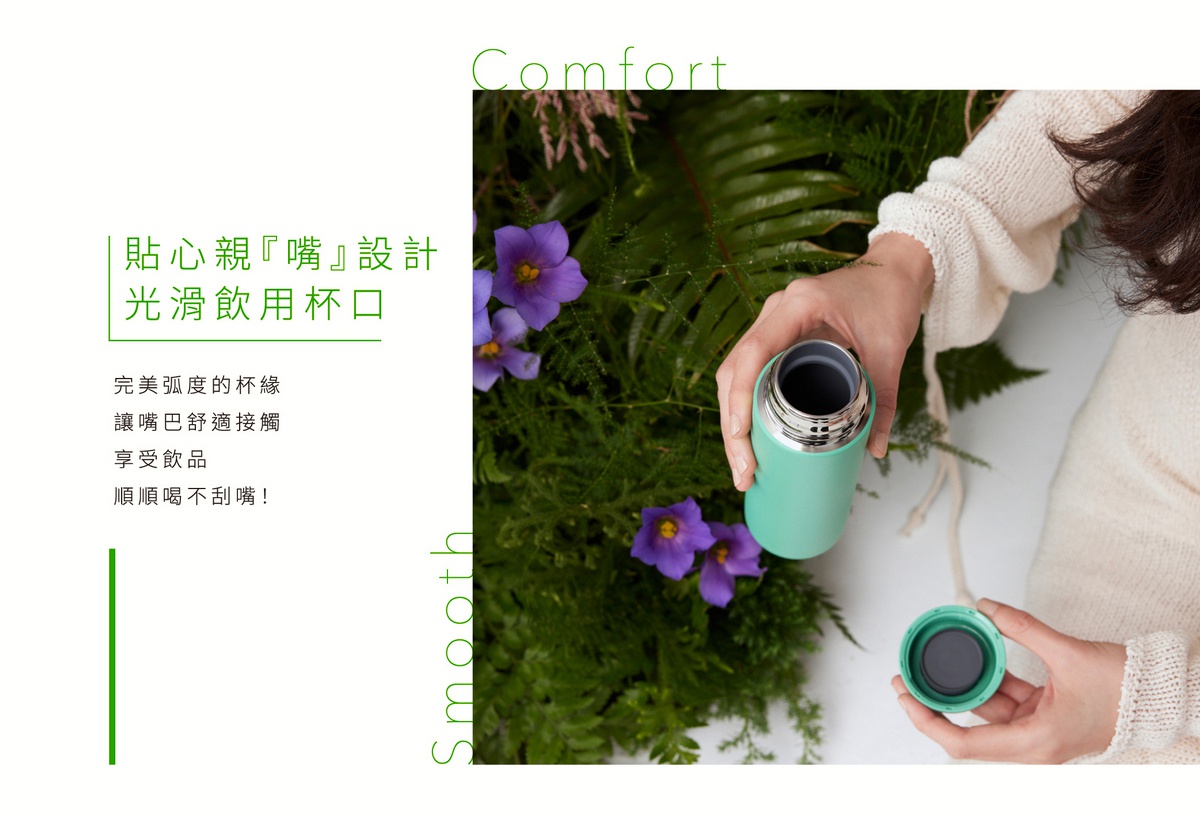 淺綠色不鏽鋼真空保溫杯，配有銀色旋蓋。一只手拿著杯身，另一只手拿著打開的杯蓋，背景是綠葉和紫色小花。