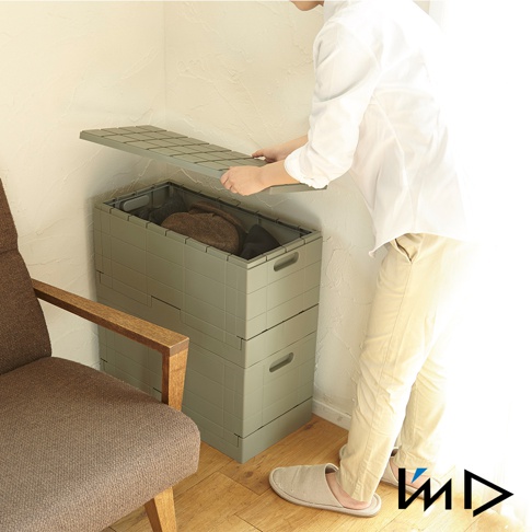 灰綠色 Grid 格子磚可堆疊摺疊收納椅，兩層堆疊，其中一層打開蓋子，內部裝有衣物。收納椅採用塑膠材質，側面有提手設計。