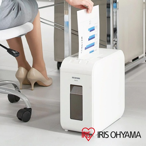 白色IRIS OHYAMA P6HCS極細碎紙機，上方進紙口正在被放入一份帶有藍色長條圖表的紙張。碎紙機前方有一個較小的觀察窗，底部有四個白色圓形腳墊。