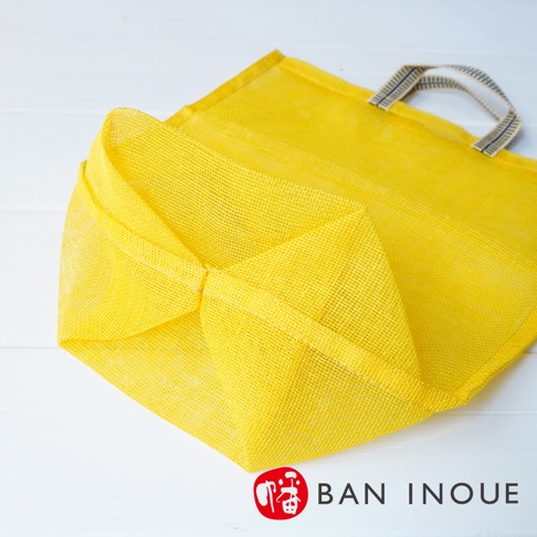 黃色網狀提把蔬果收納袋，材質為透氣網布，帶有兩個織帶提把。