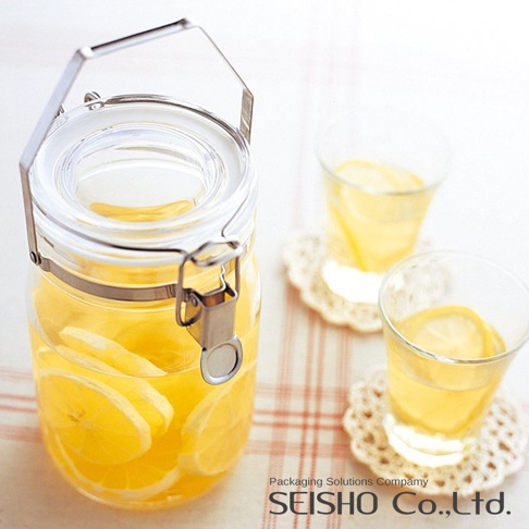 透明玻璃密封儲物瓶，瓶內裝有檸檬切片和黃色液體，瓶蓋配有銀色金屬提把與扣環。