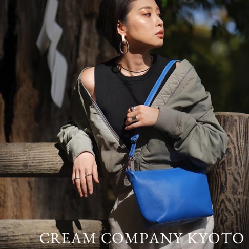 藍色皮革隨身側背包，附有藍色皮革肩帶。包款為簡潔的長方形設計，具有精緻的縫線細節。