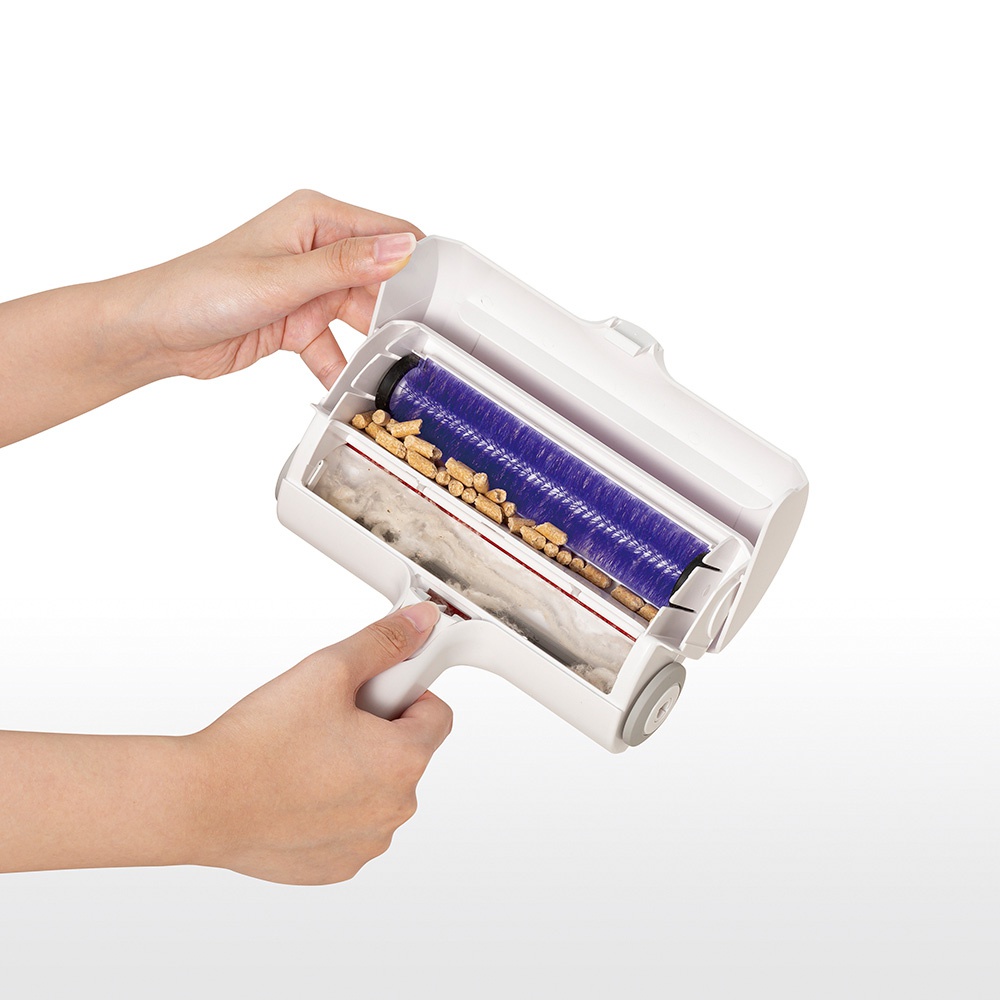 雙層除塵滾輪，白色外殼，內部有紫色刷毛滾輪和裝有毛髮、木屑的集塵盒。