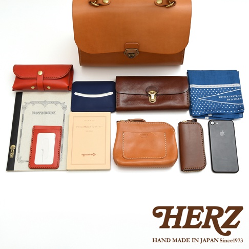 HERZ 品牌的手作皮革商品，包含錢包、筆記本、卡夾、手機及藍色印花頭巾。