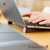 一對深棕色天然實木筆電散熱塊，放在木質桌面上，支撐著一台銀色筆記型電腦，筆記型電腦下方可見鍵盤與 USB-C 連接埠。