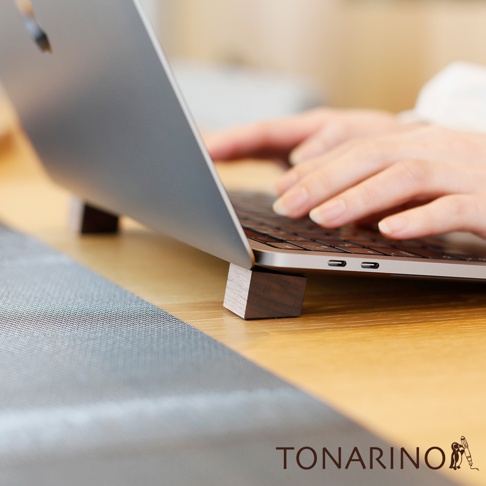 一對深棕色天然實木筆電散熱塊，放在木質桌面上，支撐著一台銀色筆記型電腦，筆記型電腦下方可見鍵盤與 USB-C 連接埠。