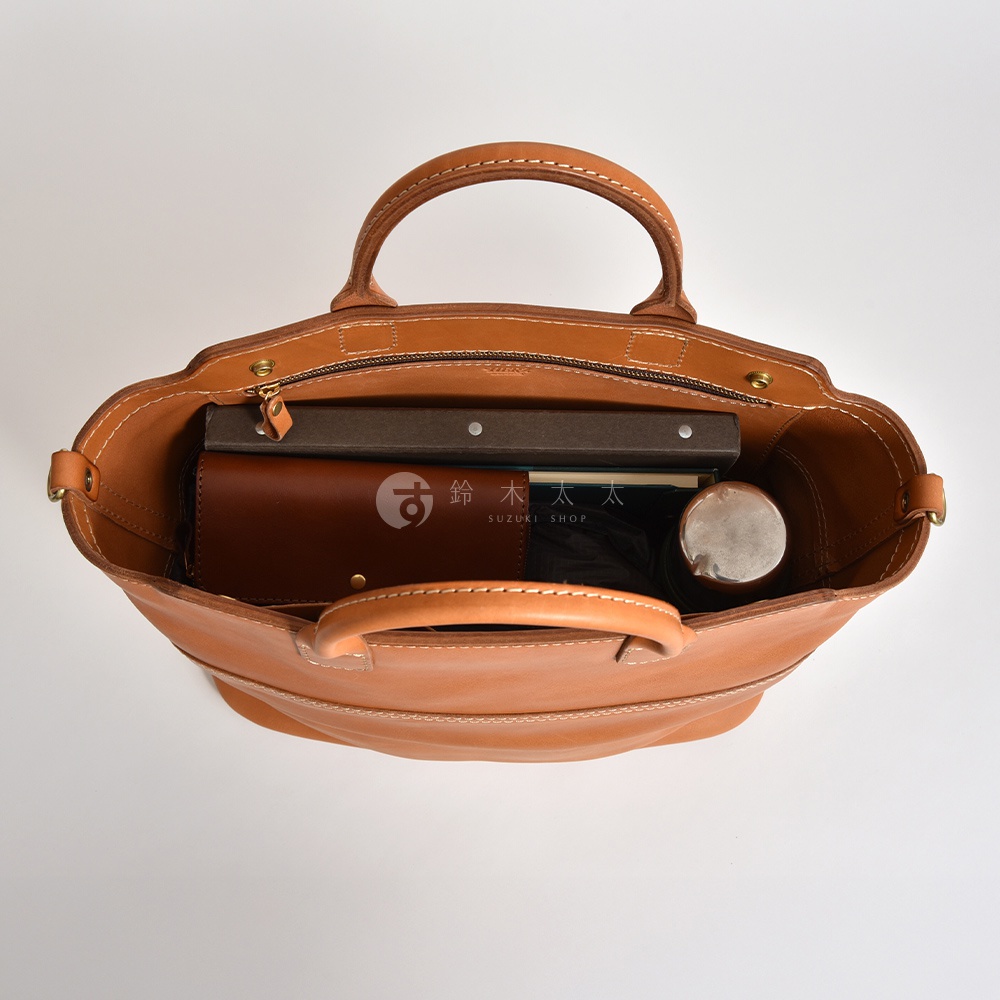 駝色皮革托特包，內部展示，裝有書籍、錢包、雨傘和水瓶。