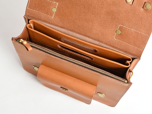 一個棕褐色的皮革橫式收納袋中袋，內部有兩層隔間，附有拉鍊開合及金屬扣。