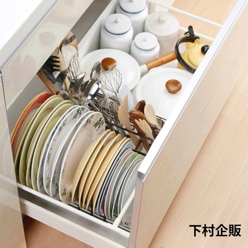 一個裝有各式餐具的伸縮碟盤整理架，包含多個白色陶瓷罐、金屬鍋具、木製餐具、打蛋器及不同尺寸與花紋的盤子，整體呈現在開放的廚房抽屜內。