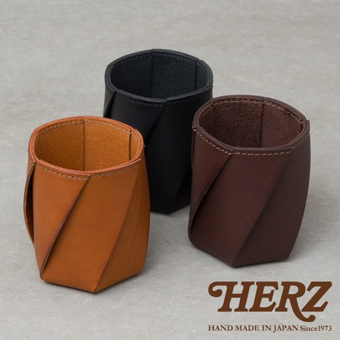 三款職人手作皮革Organ六角收納筆筒，包括淺棕色、黑色和深棕色，以扭轉的皮革設計呈現，用於桌面收納。