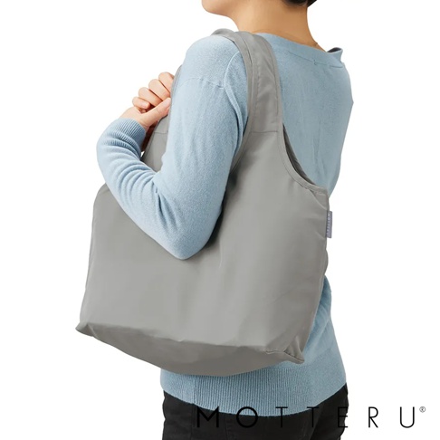 一位身穿淺藍色毛衣的女士，肩背一個淺灰色、光滑材質的摺疊保冷可拆托特袋，袋子容量約為15公升。