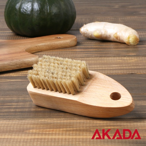 AKADA 品牌天然豬毛蔬果刷及纖毛蔬果刷的近景圖，展示了木製手柄和刷毛，背景有南瓜和生薑。