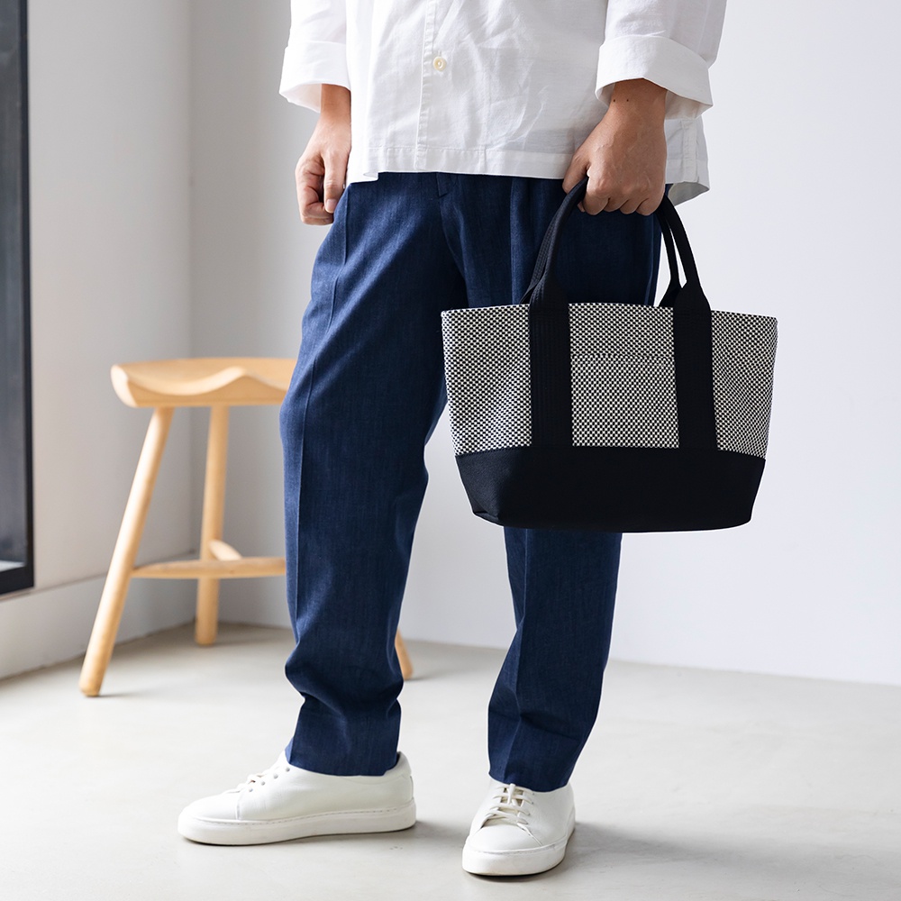 黑色底部配有三河木綿刺子織圖案的迷你托特包，黑色提把，風格簡約。