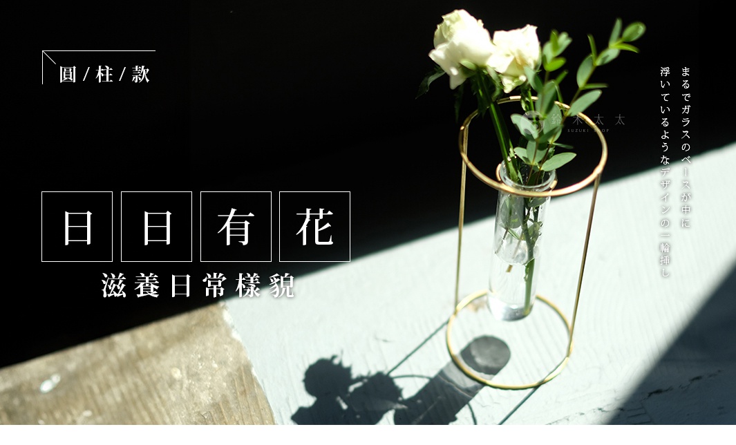 黃銅圓柱形玻璃花器，支架為金色，內含兩朵白色玫瑰及綠葉。