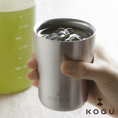 手持日製18-8不鏽鋼雙層隔熱保冰隨行杯，杯身呈現銀色霧面金屬質感，內裝有冰塊和液體。杯子上印有「KOGU」品牌標誌。