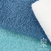 藍色與青綠色長纖毛巾特寫，質地蓬鬆柔軟，右側疊放一條白色毛巾，右下角有「泉」字樣的白色品牌標誌及「SENSHU TOWEL」字樣。