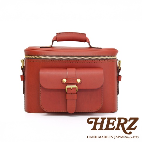 HERZ 品牌復古紅色皮革相機包，帶有翻蓋口袋和金色扣環，頂部有提把。