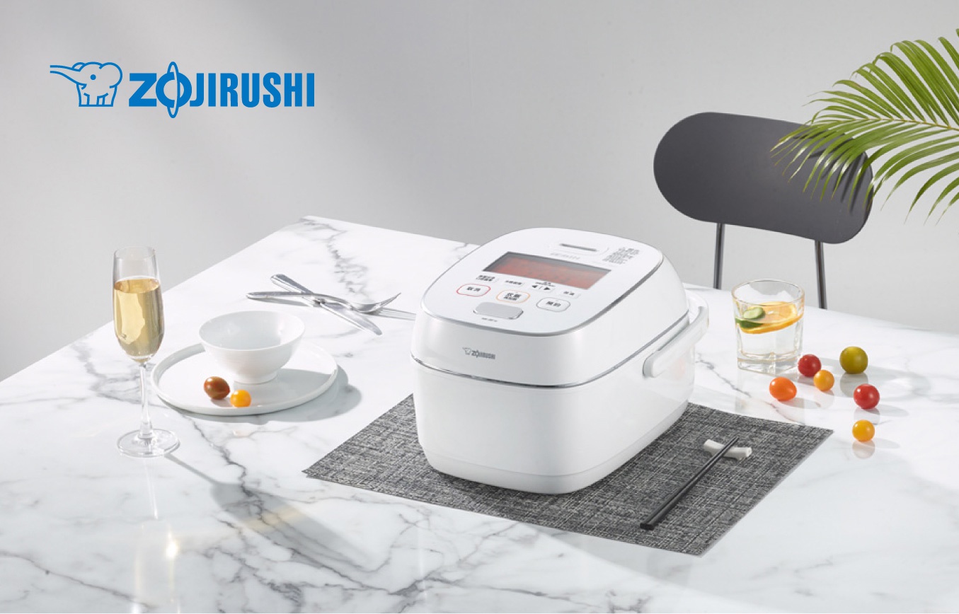 象印鐵器塗層白金厚釜壓力IH電子鍋(NW-JBF10)，白色機身，頂部有紅色顯示螢幕與多個操作按鈕，置於灰色餐墊上。