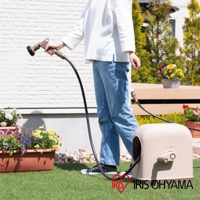 淺米色圓潤造型的家用全覆蓋水管車，設有米色捲軸手柄，連接黑色軟管，用於庭院澆水。