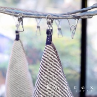 兩條 SWELL 質感波浪鬆餅紋方巾，一條為深棕色與白色條紋，另一條為淺灰色與白色條紋，皆以深藍色織帶掛於金屬曬衣夾上。