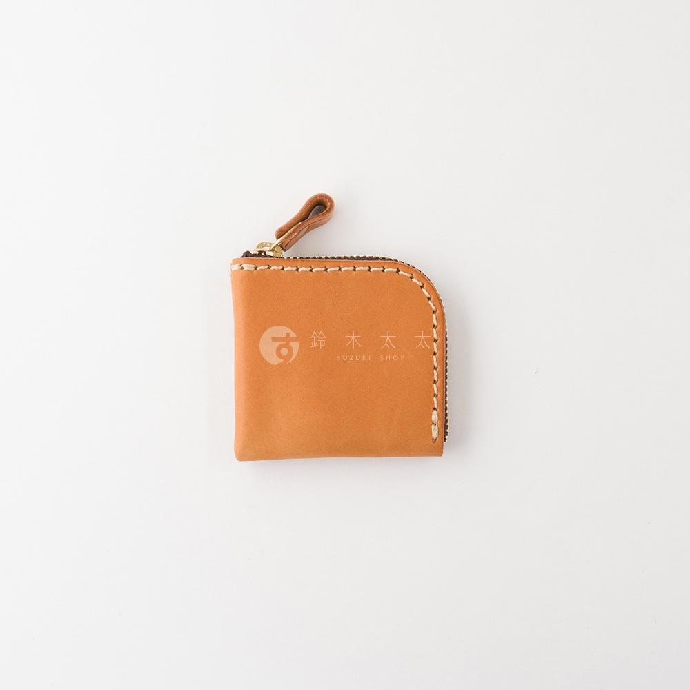 日本HERZ職人手作皮革分隔收納零錢包，選用優質Stare皮革製成，呈現自然焦糖色澤，方形包體搭配圓角與精緻手工縫線，頂部配有拉鍊與皮革拉環，表面印有鈴木太太商標。