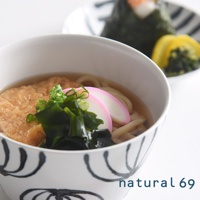 手繪丼碗，白色陶瓷碗身飾有黑色線條圖案，碗內盛有日式烏龍麵、炸豆腐、海帶和魚板。