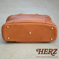 職人手作皮革Organ兩用商務托特包 G-61，採用溫潤的焦糖棕色皮革，包身底部有五個金屬腳釘，展現精緻工藝。