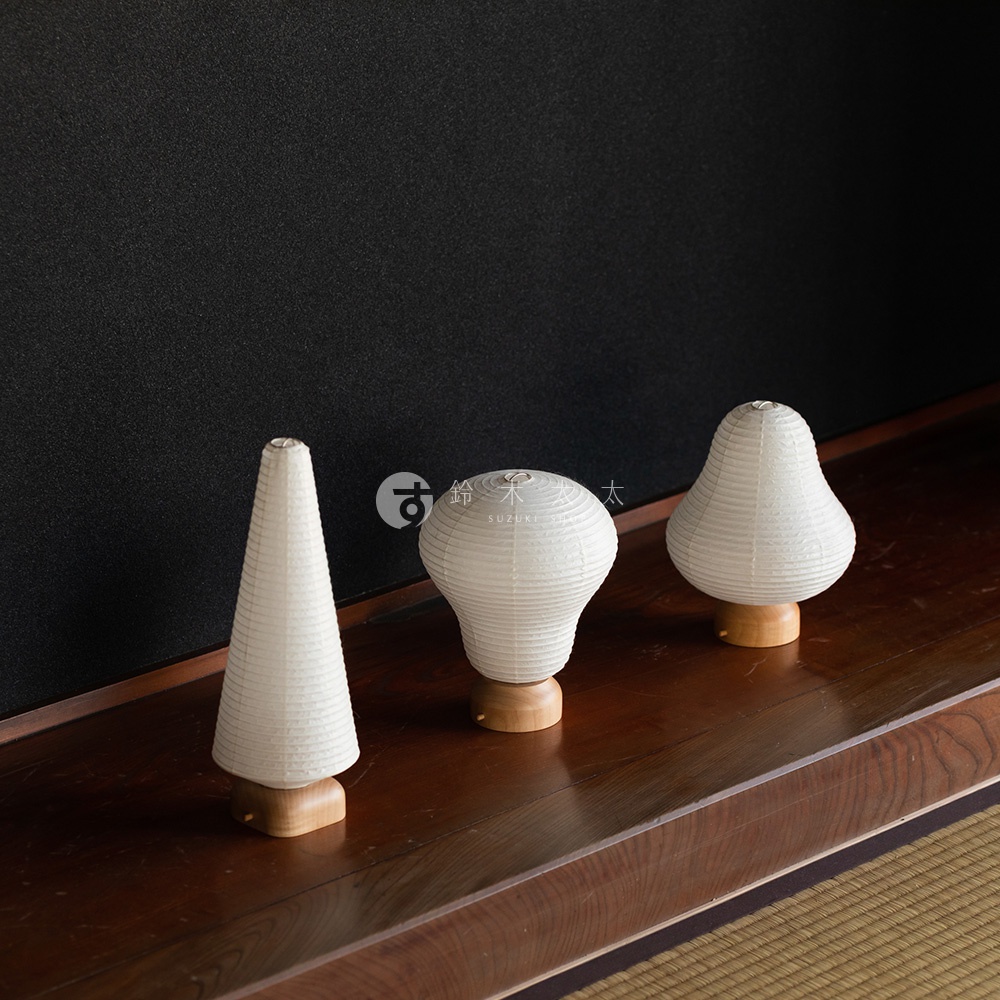 三款日式和紙提燈，分別為錐形、燈泡形及梨形，皆為白色，底部為木質底座，置於木質檯面上。