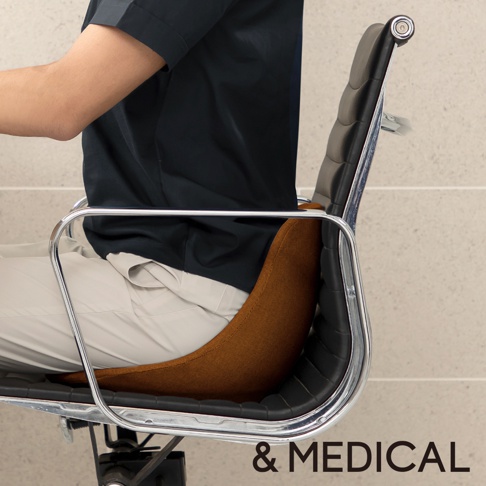 舒腰正姿座墊 HB 高背款，採用織物材質，提供腰部支撐。座墊呈弧形，顏色為棕褐色，放置於黑色皮質辦公椅上。