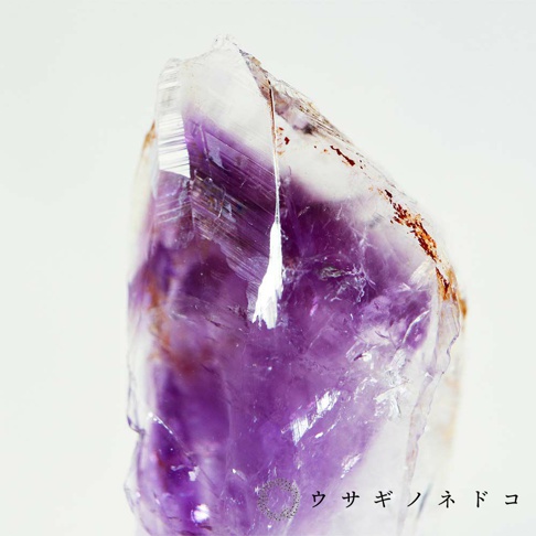 紫水晶礦石，帶有天然的紫色漸層與部分雜質，晶體結構清晰可見，表面有光澤。
