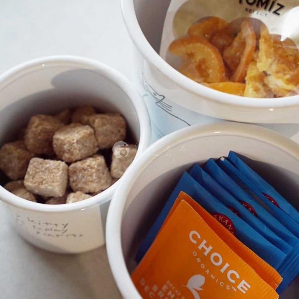 CAT&DOG 琺瑯儲物罐，白色罐身，其中一個裝有方塊狀的紅糖，另一個裝有橘色和藍色包裝的茶包或咖啡包。