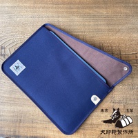 深藍色純綿帆布平板收納包，內裡為棕色，設有磁扣，包上印有日文標誌。