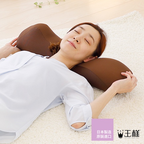 咖啡色舒背拉伸枕，採用柔軟材質，具有特殊弧度設計，能支撐頸部與脊椎，適合平躺使用。