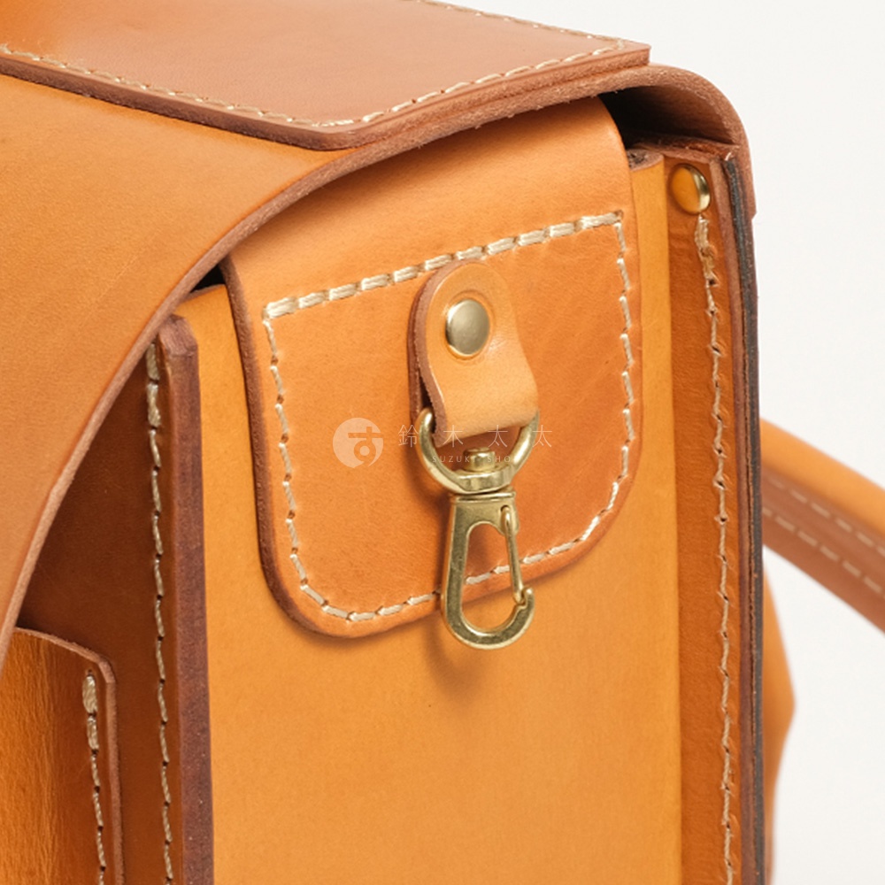 職人手作皮革橫式書包的細節，包含縫線、金屬扣環和皮革紋理。